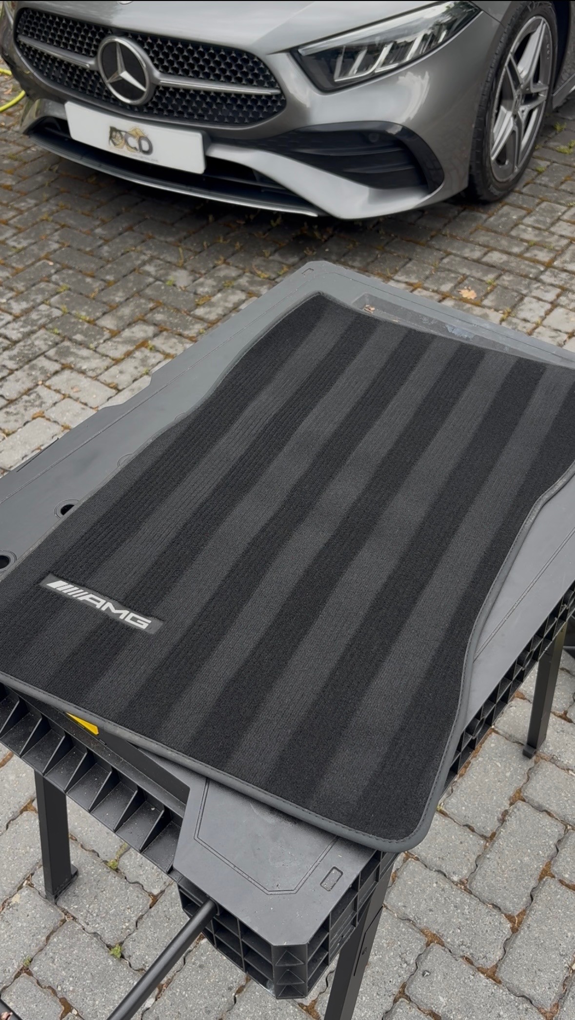 AMG floor mat deep cleaned with Mercedes CLS in background